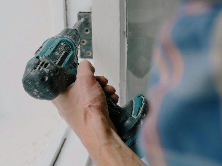 Eine Hand hält einen Akku-Schrauber, bereit zum Befestigen eines Schraubenzubehörs.